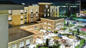 A hotel courtyard with outdoor seating, a fire pit, and a tennis court. - Homewood Suites by Hilton Poughkeepsie (Poughkeepsie)