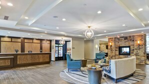 A hotel lobby with a reception desk, seating area, and a stone fireplace. - Homewood Suites by Hilton Poughkeepsie (Poughkeepsie)