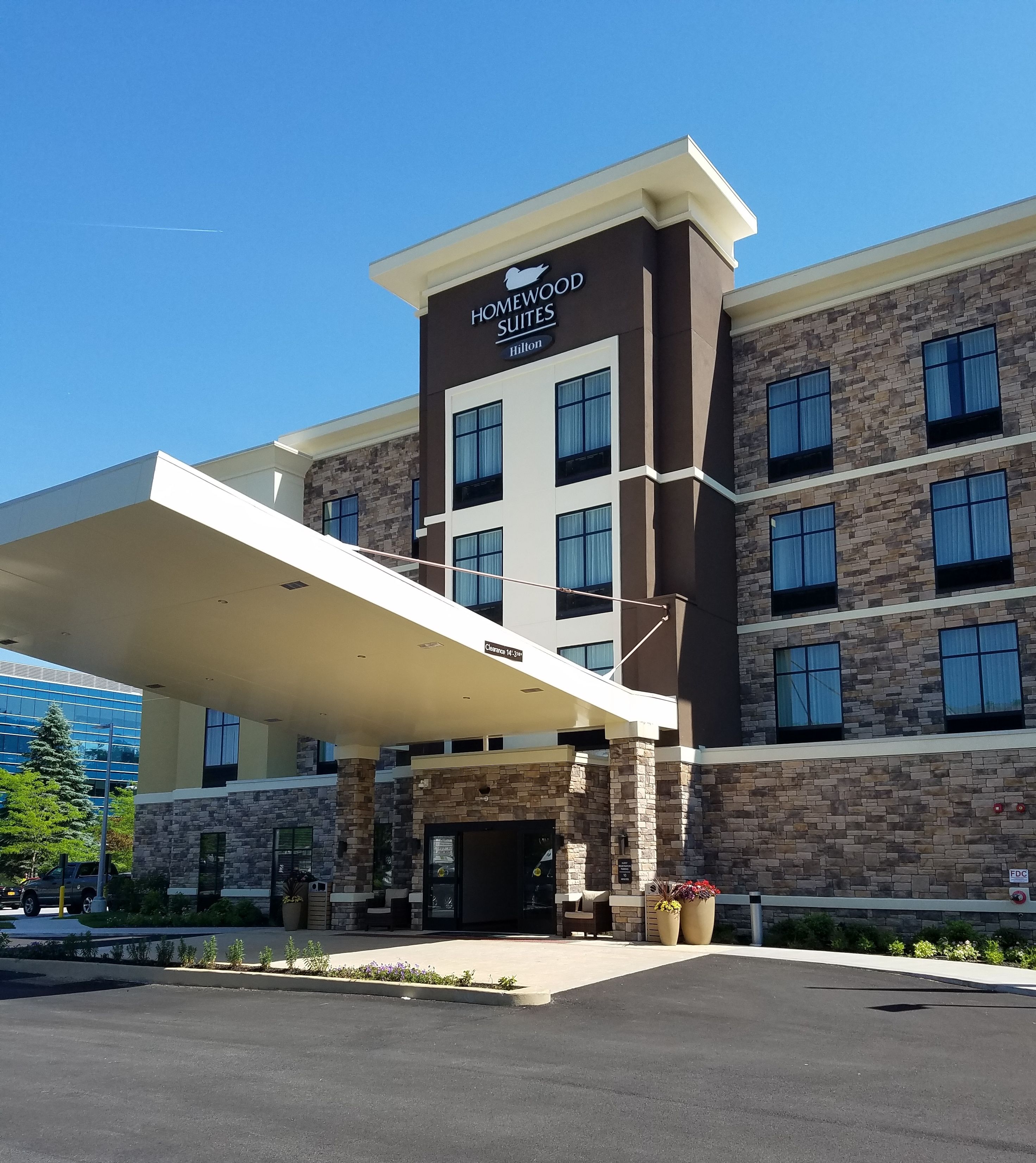 A hotel with a modern design, featuring a stone facade and a clear sign for "Homewood Suites" by Hilton.
