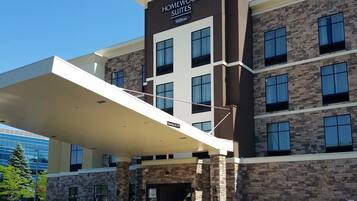 Ein Hotel mit modernem Design, das eine Steinfassade und ein deutliches Schild für "Homewood Suites" by Hilton zeigt.