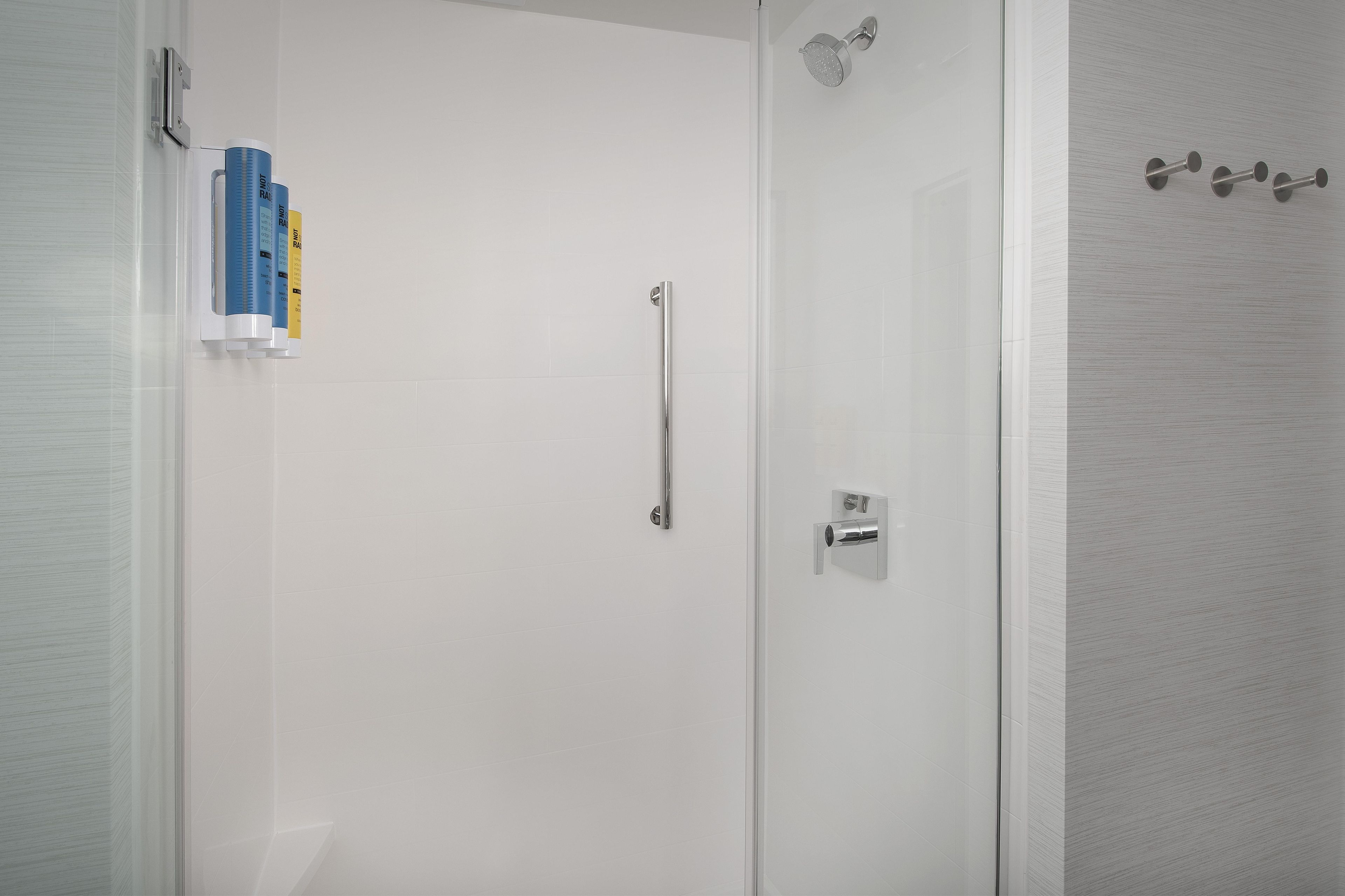 A bathroom with a glass door, a towel rack with a towel, and a shower head.