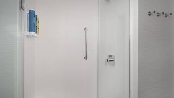 A bathroom with a glass door, a towel rack with a towel, and a shower head.