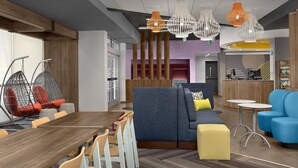 A modern interior with a dining area, seating arrangements, and a reception desk. - Tru by Hilton Orangeburg (Orangeburg)