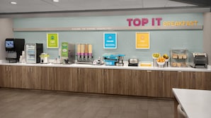 A breakfast counter with a sign reading 'TOP IT BREAKFAST,' a coffee machine, a yogurt dispenser, and various food items. - Tru by Hilton Orangeburg (Orangeburg)