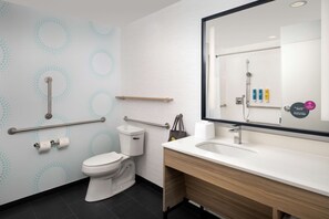 A modern bathroom with a white toilet, a sink with a mirror, and a shower area. - Tru by Hilton Orangeburg (Orangeburg)