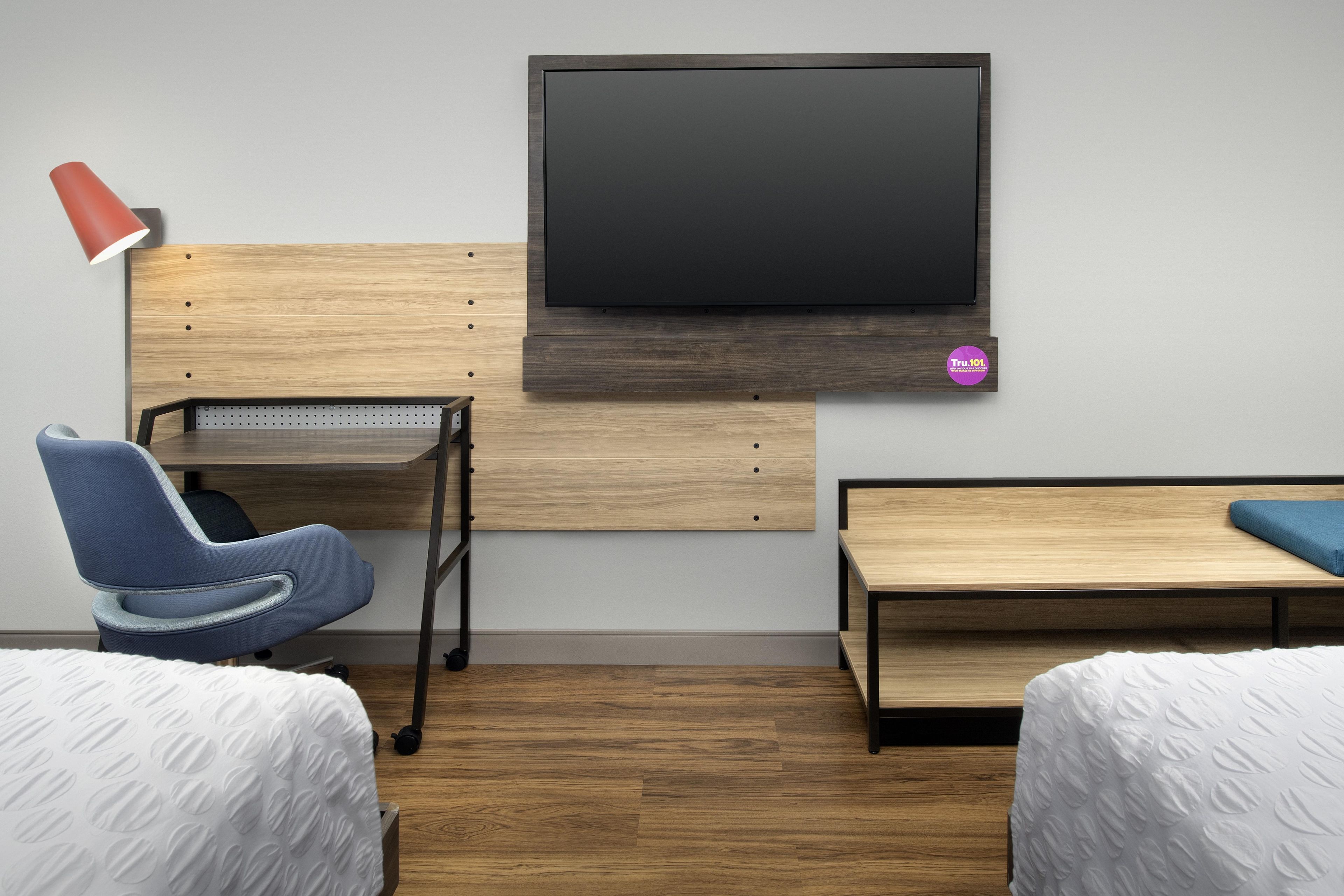 Una habitación de hotel con cama, escritorio, silla, televisor y una mesita.