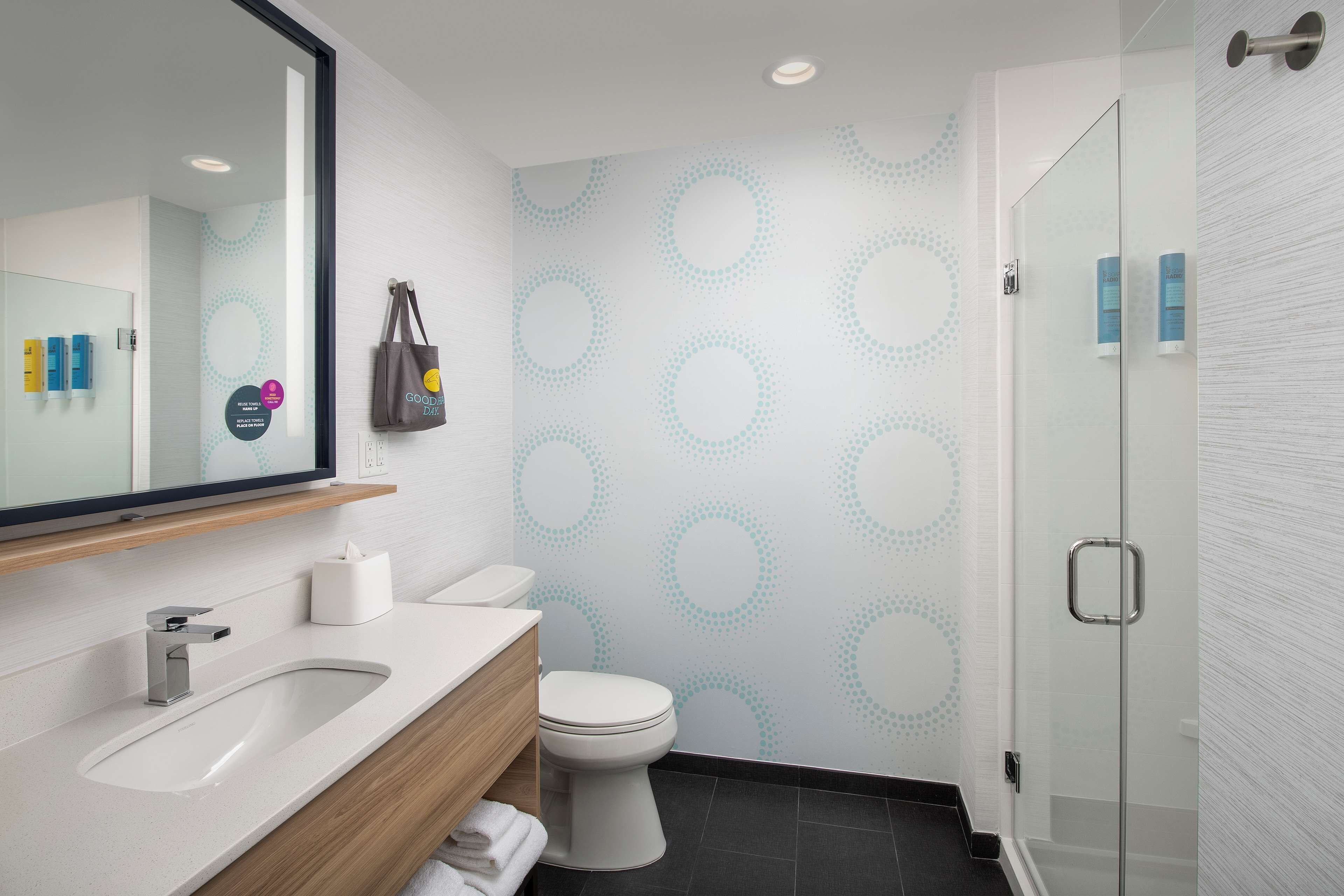 Un baño moderno con un espejo grande, un lavamanos, un inodoro y una cabina de ducha de vidrio.