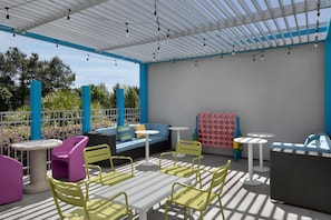 An outdoor patio area with seating arrangements, a table, and a wall with a patterned design. - Tru by Hilton Orangeburg (Orangeburg)