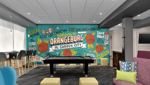 A pool table in a room with a colorful mural, chairs, and a sofa. - Tru by Hilton Orangeburg (Orangeburg)