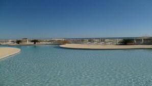 A clear blue pool with lounge chairs and a sandy area, surrounded by a fence. - Gulf Shores Plantation ~ Resort Conference Center #1169  (Gulf Shores)