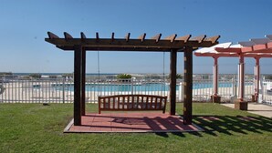 A wooden pergola with a bench overlooking a swimming pool area. - Gulf Shores Plantation ~ Resort Conference Center #1169  (Gulf Shores)