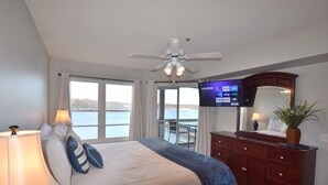 Une chambre avec un lit, une télévision, un ventilateur de plafond et une vue sur l’eau.
