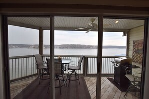 A balcony with a view of a lake, a grill, and a table with chairs. - SUNSET VIEW FOR MILES! Main Channel 2 Bed, 2 Bath-Sleeps 6- VERY CLEAN! (Osage Beach)