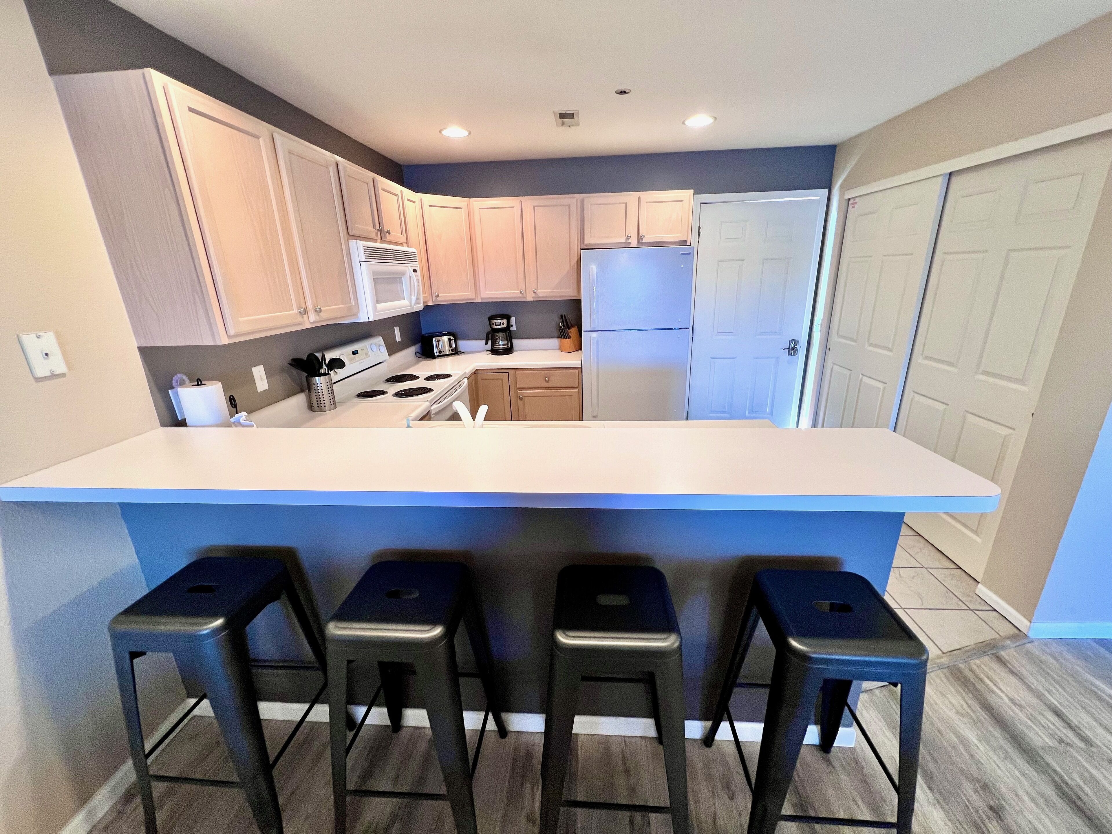 Una cocina moderna con una isla central, armarios de madera, un refrigerador y una cafetera.