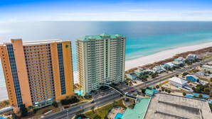 Ein Hochhaus-Hotel mit mehreren Etagen und einem Poolbereich, direkt neben einem Strand und dem Ozean.