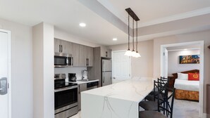 A modern kitchen with a central island, stainless steel appliances, and a dining area with chairs. - 2 Bedroom Resort Condo  at Highrise Walking distance to UNIVERSAL (Orlando)
