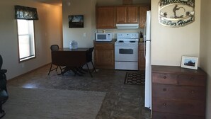 A kitchen with wooden cabinets, a microwave, an oven, and a dining table with chairs.