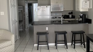 Uma cozinha moderna com uma ilha central, banquetas e um ventilador de teto.