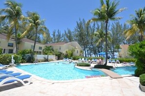 Ein Poolbereich mit mehreren Pools, Liegestühlen und Palmen.