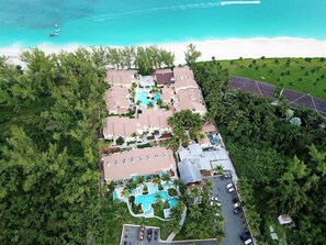 Vue aérienne d’un complexe hôtelier comprenant plusieurs bâtiments, une piscine et une plage.