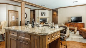 Un salon spacieux avec un grand îlot central en bois, une cheminée et un téléviseur.