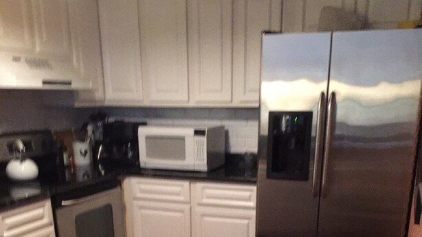 A kitchen with white cabinets, a stainless steel refrigerator, a microwave, and a trash can. - Sea Colony Tennis Villa - Near the beach (Bethany Beach)