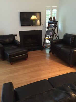 Relax in a comfortable seating area with a sofa set and enjoy entertainment options with a mounted TV above the fireplace.