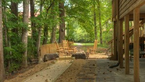 Un espacio al aire libre cubierto con un sendero de piedra, sillas de madera y una valla de madera.