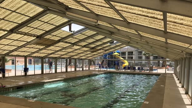 En inomhuspool med ett tak som skyddar mot väder och vind, klart vatten och en rutschkana i bakgrunden.