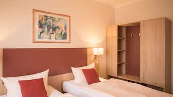 Ein Hotelzimmer mit zwei Betten, einem großen Holzschrank, einem an der Wand hängenden Gemälde und einer Nachttischlampe.