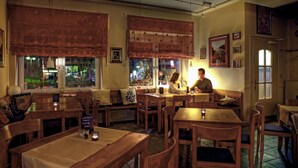 Un restaurante acogedor con muebles de madera, ventanas amplias con cortinas y vistas al exterior.