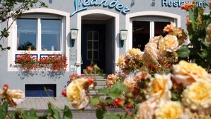 Un restaurante llamado "Leander" con una fachada clásica, ventanas grandes y jardineras con flores.