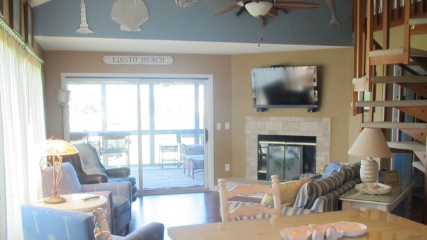 Uma sala de estar com lareira, televisão na parede e uma placa com a inscrição 'EDISTO BEACH'.