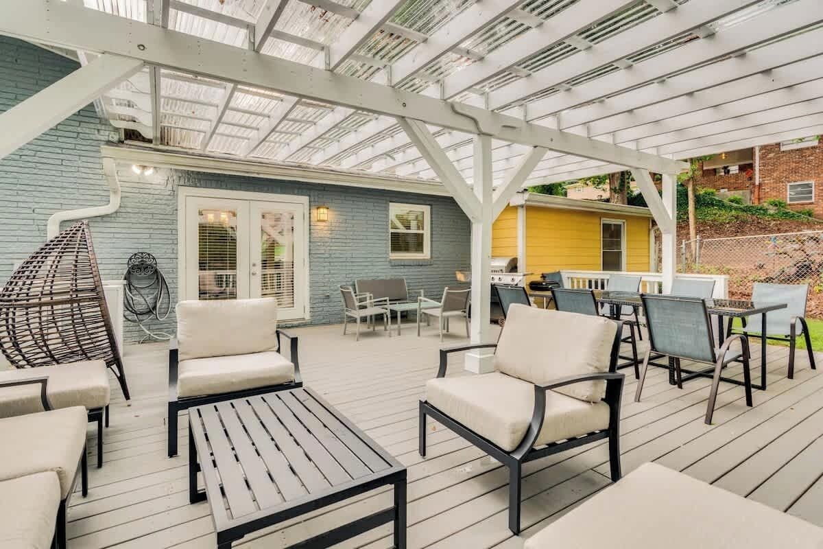 Une terrasse extérieure dotée d’un espace salon couvert, d’un barbecue et, en arrière-plan, d’un bâtiment bleu.