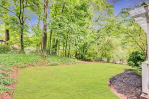 A well-maintained garden with a lawn, trees, and a pathway leading to a building.