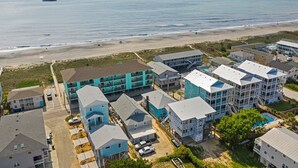 A coastal residential area with multi-story buildings, a beach, and a clear sky. - "Sand Dollar Suites" suite 4: A short stroll from our sandy shores! (Carolina Beach)