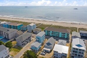 A coastal residential area with multi-story buildings, a beach, and a clear view of the ocean.