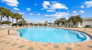 Una piscina con sillas de descanso y palmeras.
