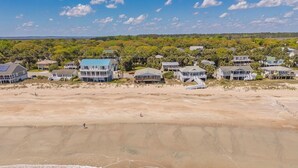 A coastal residential area with beachfront houses, sandy beach, and ocean waves.