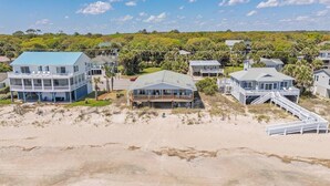 A beachfront property with multiple houses, including a large two-story building with a blue roof and a smaller house with a grey roof.
