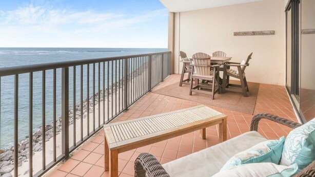 Ein Balkon mit Meerblick, einem Tisch, Stühlen und einer Couch.