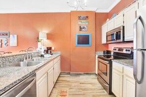 A kitchen with granite countertops, stainless steel appliances, and white cabinetry. - Grand Pointe 502- Gulf-front, water on 2 sides (Orange Beach)