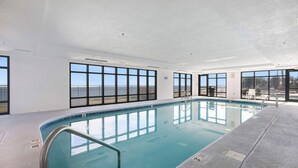 Ein Innenpool mit freiem Blick durch große Fenster, mit Fliesenboden und einer Metallleiter.