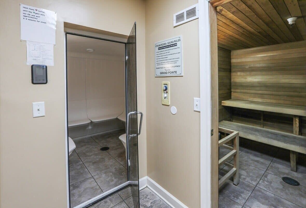 Een stoomruimte met sauna-regels op de muur, een douchegedeelte en houten banken.