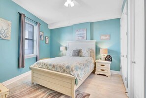 A bedroom with a bed, nightstands, and a window with curtains.