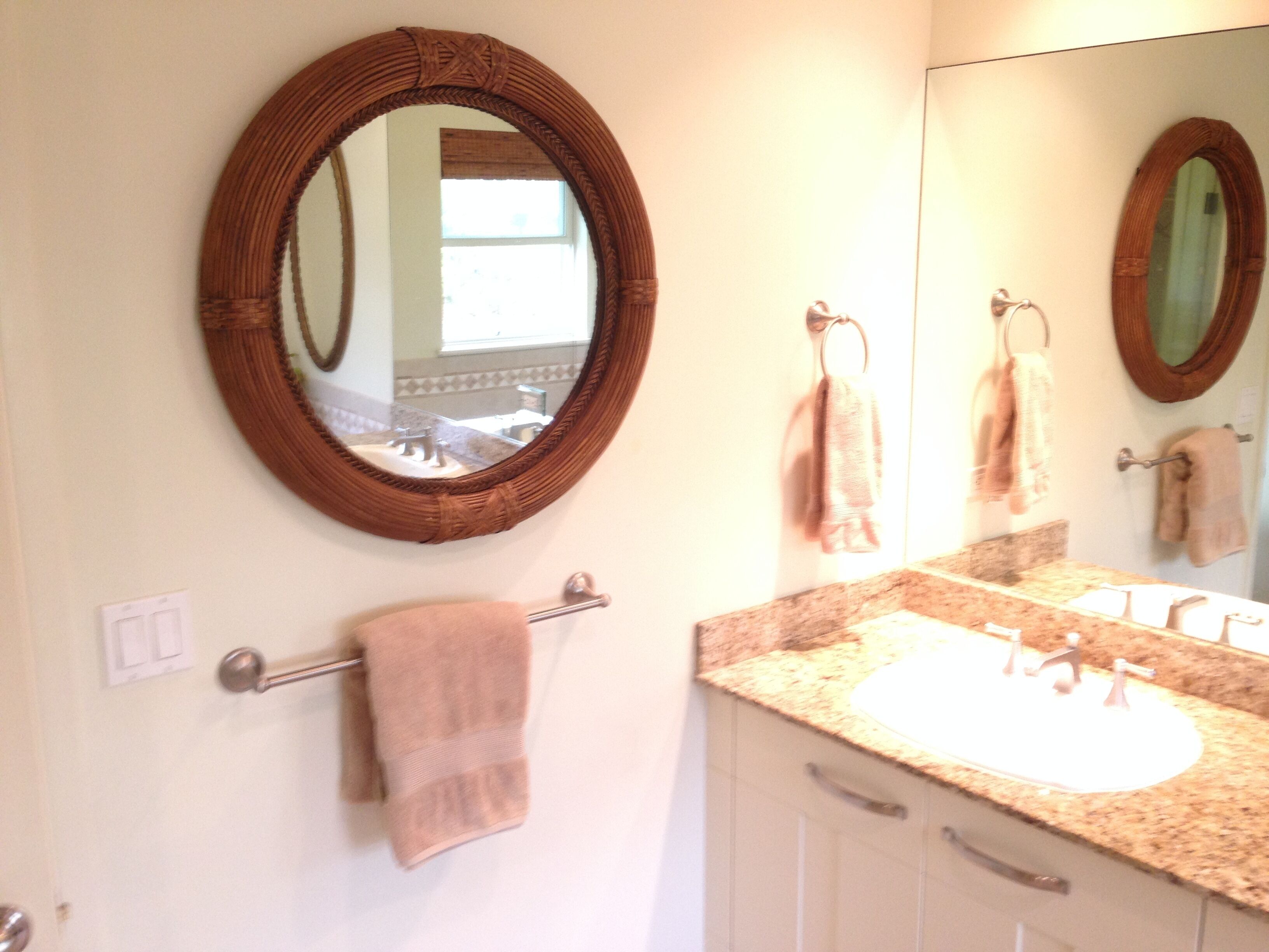 A bathroom with a round mirror, a sink, and a towel rack.