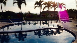 A swimming pool with palm trees and a building in the background. - AWESOME OCEANVIEW 3 BEDROOM 3 BATH TOWNHOME UNBEATABLE LOCATION (Kailua-Kona)
