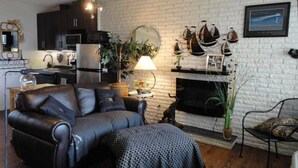 Un salon avec une cheminée, un canapé, une table à manger et un coin cuisine.