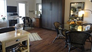 Un vaste espace de vie doté d’un plancher en bois, d’une table à manger avec des chaises, d’une grande armoire en bois foncé, d’un téléviseur et d’un miroir mural.