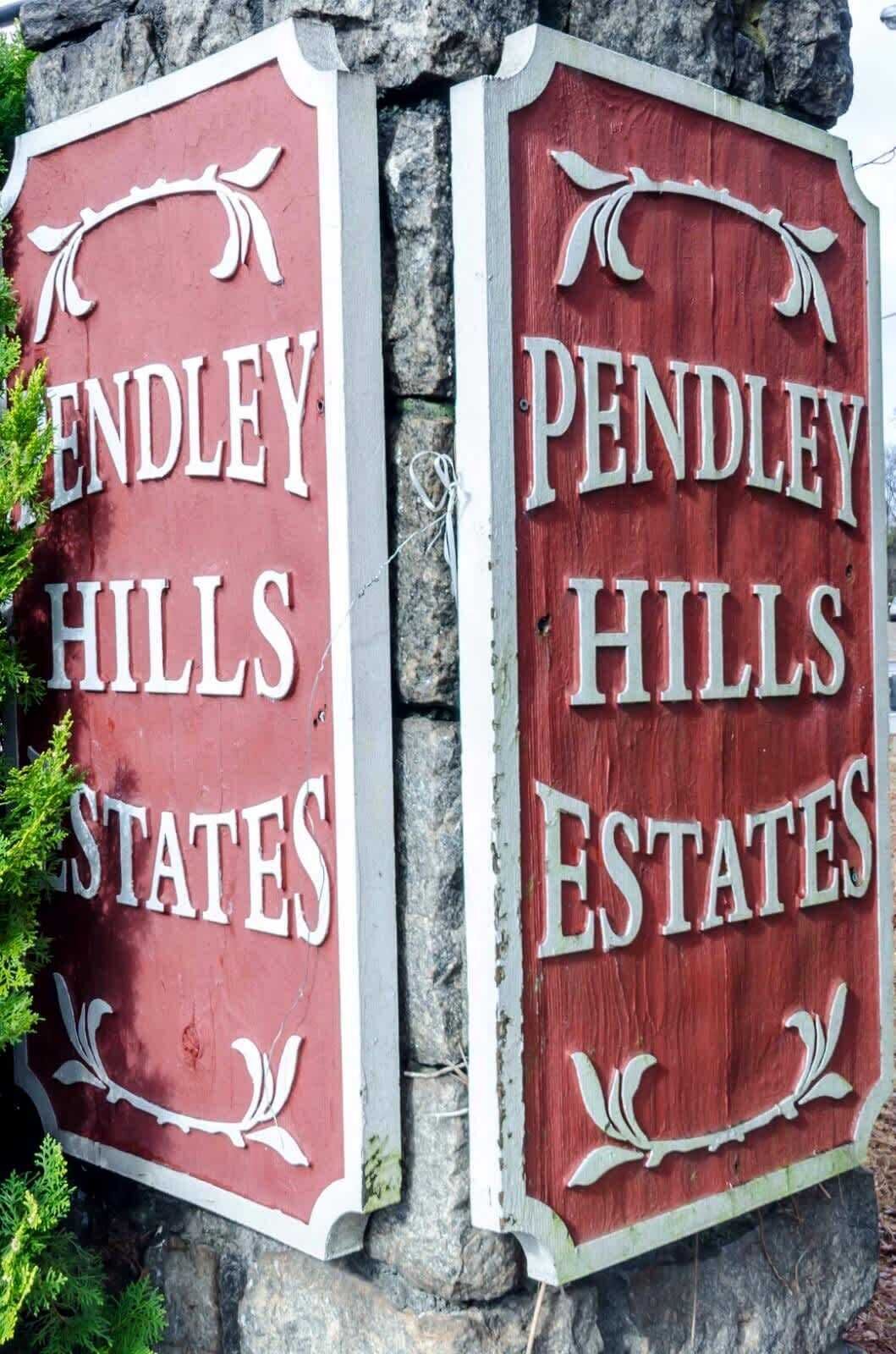 Two signs for Pendley Hills Estates, mounted on a stone wall.